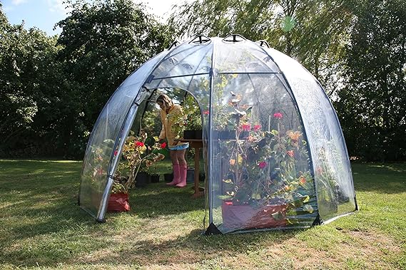 dome greenhouse with women watering plants inside.